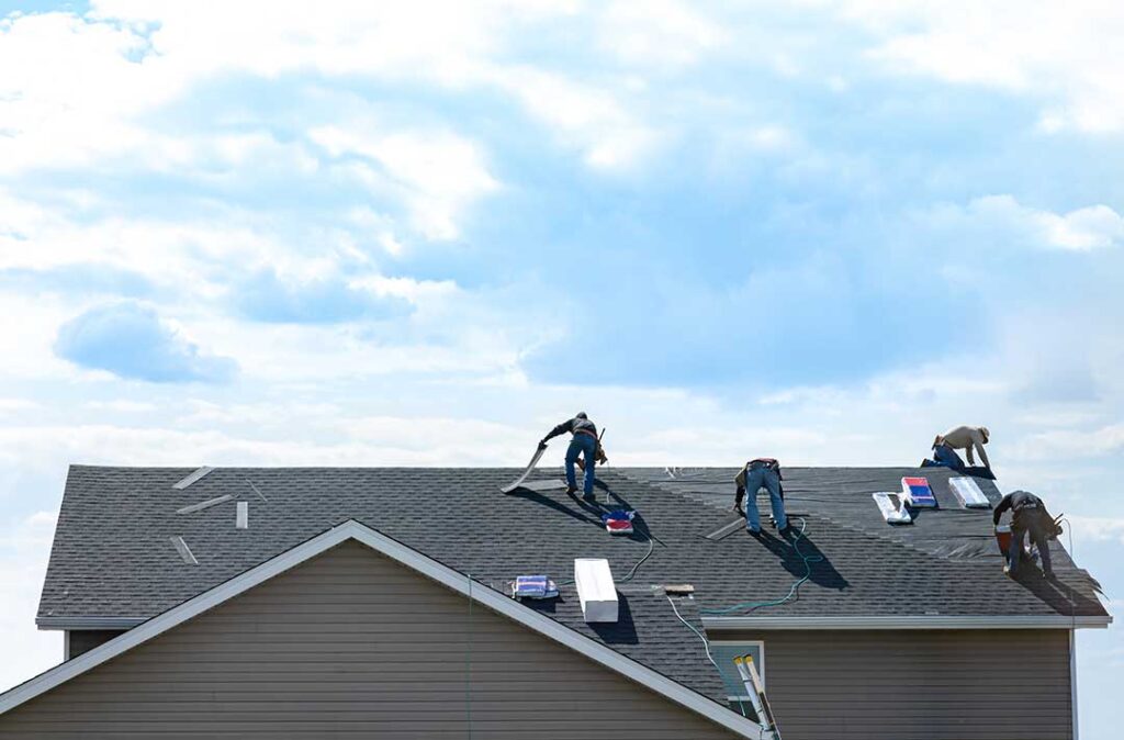Wet ceiling stain beneath a roof leak, with damaged shingles and damp attic insulation visible nearby.
